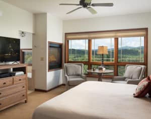 Bedroom with neutral tones and large windows with a mountain view.